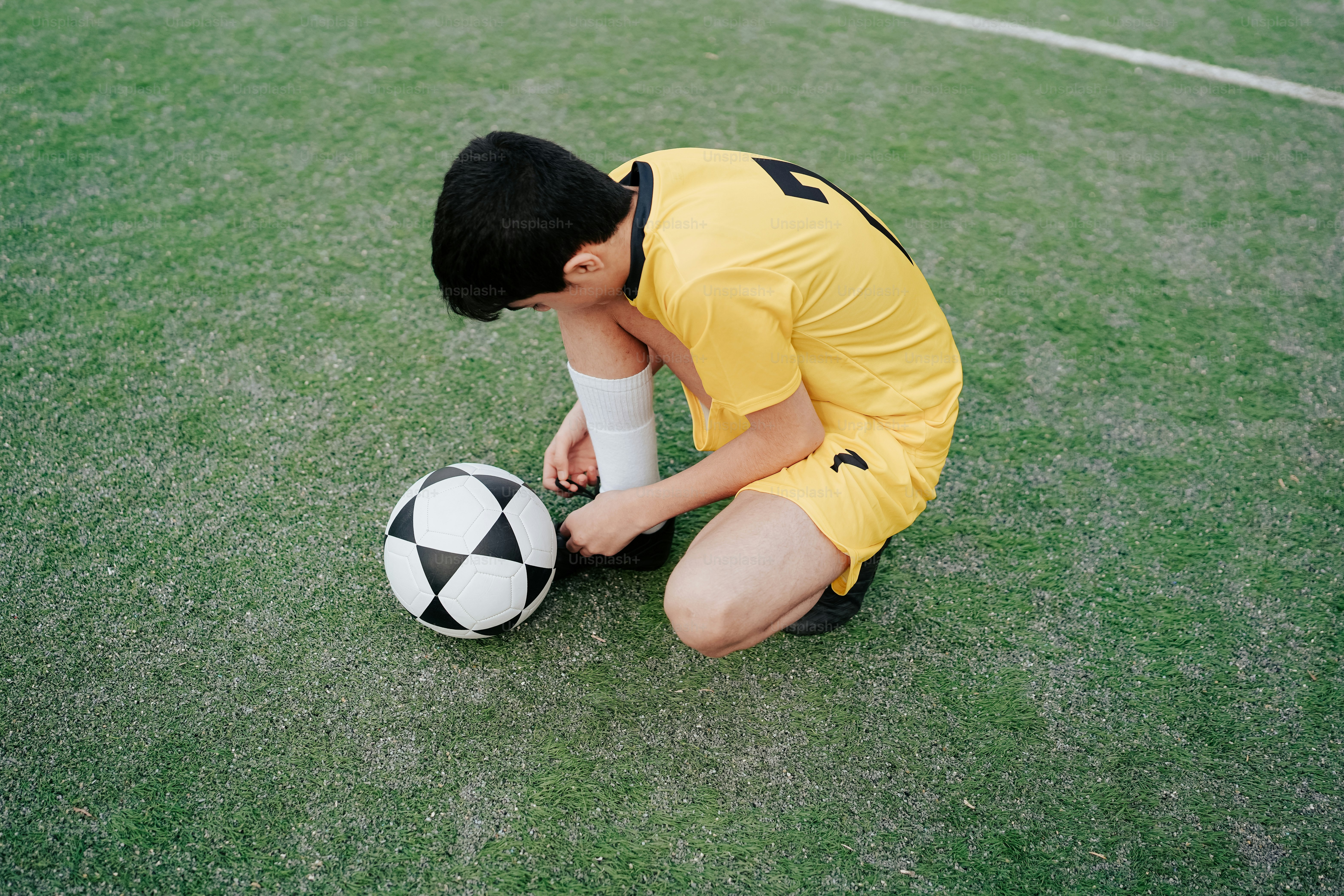 a young man kneeling down next to a soccer ball